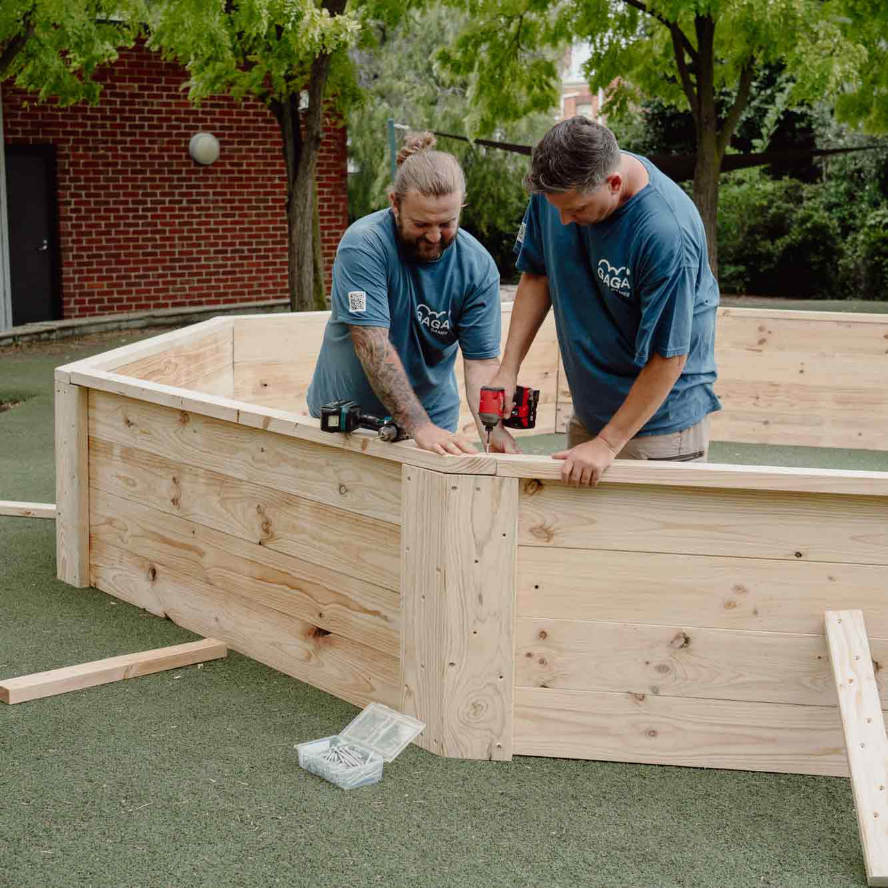 Two Gaga Games representatives installing a DIY Gaga Pit kit at a client's location.